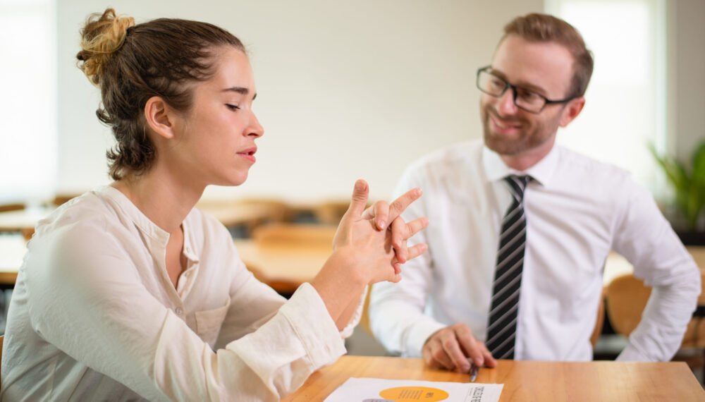 Coworkers discussing business issue. Business man talking with female colleague with blurred office interior in background. Colleagues concept.