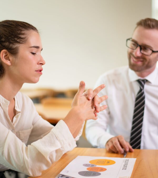 Coworkers discussing business issue. Business man talking with female colleague with blurred office interior in background. Colleagues concept.