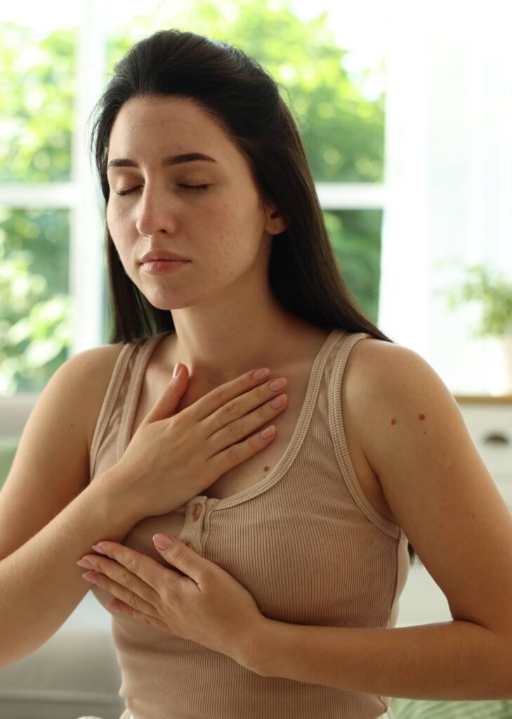 Mujer en respiración consciente con sus manos en el pecho, una debajo de la otra.